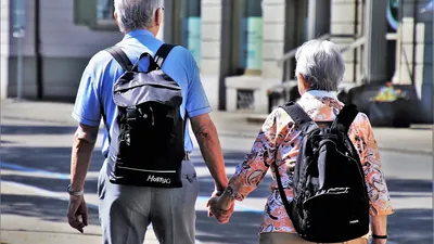Older couple holding hands while walking, seen from behind
