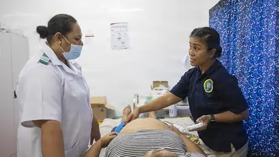A health worker examining a pregnant woman during a prenatal visit