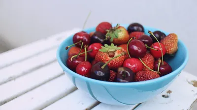 Bowl of fresh cherries and strawberries on a white table