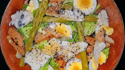 Plate of salad with romaine lettuce, sliced eggs, herring and asparagus