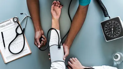 Health care worker measuring a patient's blood pressure with a cuff and stethoscope