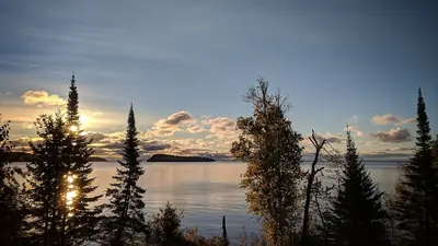 A calm lake at sunset framed by trees